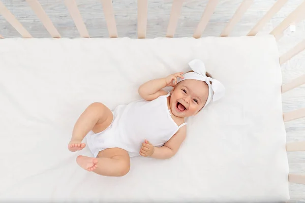 개월된 여아는 유아용 침대에 웃으며 카메라를 아기의 — 스톡 사진