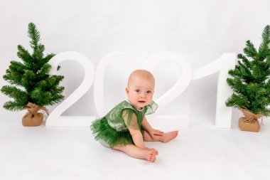 Christmas photo small child girl sitting near Christmas trees and numbers 2021 on a white isolated background, happy new year 2021, space for text. clipart