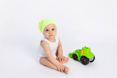 Beyaz bir arka planda beyaz elbiseli yakışıklı bir çocuk daktiloyla oynuyor, çocukların erken gelişimi, oyuncakların arasında sekiz ay, mesajlaşma için yer var.