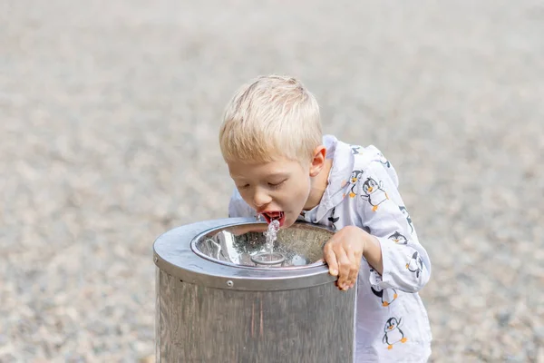 Een Blonde Jongen Drinkt Water Uit Een Waterdispenser Zomer Bij — Stockfoto