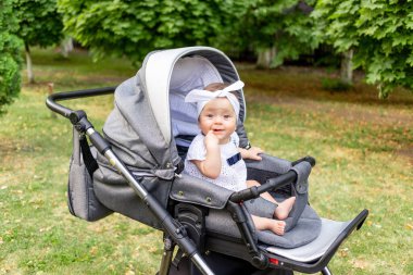 Küçük bir çocuk. 7 aylık bir kız yazın bebek arabasında oturuyor ve kameraya bakıyor.