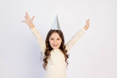 Doğum gününde kollarını açmış şapkalı genç bir kız izole edilmiş beyaz bir arka planda çığlık atıyor mutlu bir yüzle gülümseyen güzel bir kız.