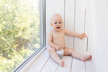 8 aylık bebek bezi içinde beyaz bir yatakta yatıyordu. Ev bacağında bir şişe süt vardı. Top view, bebek maması konsepti, biberondan bebek içme suyu, mesaj atmak için yer.