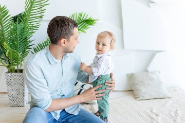 Baba küçük bir çocukla konuşur. 1 yıl, mutlu aile kavramı, babalar günü, baba-oğul ilişkisi..