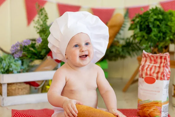 a baby in a cook\'s hat sits in a beautiful photo zone with flour and vegetables, a baby cook, a child with flour and bread prepares food