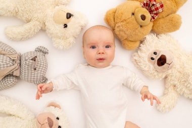 Beyaz arka planda peluş ayı oyuncaklarıyla bir çocuğun portresi. Oyuncakların arasında 6 aylık bebek. Metin için boşluk