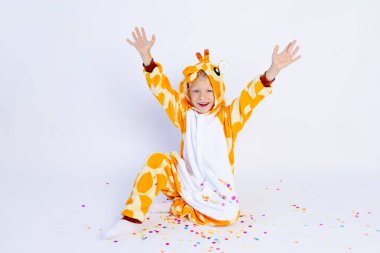 Komik, parlak zürafa kostümü giymiş küçük bir çocuk konfetiyle izole edilmiş beyaz bir arka plan, çocukların doğum günü, mesajlaşma yeri.
