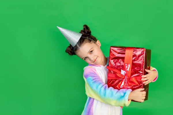 一个可爱的小女孩 穿着鲜艳的西服 戴着一顶带着礼物的帽子 背景是绿色孤立的 文字空间 新年及圣诞概念 — 图库照片