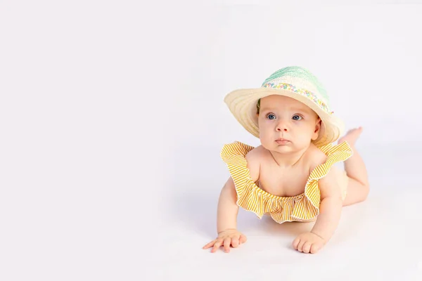 身着泳衣 头戴太阳帽 面带微笑的女婴 6个月大 躺在与世隔绝的白色背景上 可供阅读 — 图库照片