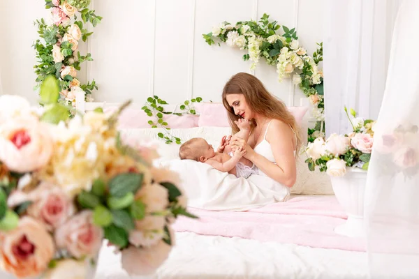 Genç bir anne çocuğunu kollarında tutar ve bacaklarını öper. Güzel bir iç mekan olan çocuğa sevgi ve bakım kavramı.