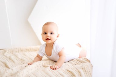 Küçük bir çocuk. Bir çocuk, parlak bir odada yüzüstü yatar ve gülümser.