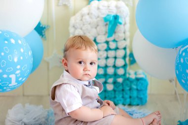 Doğum günü çocuğu. 1 yaşında bir çocuk, taşaklı bir bebek ve takım elbiseli ve papyonlu bir numara.