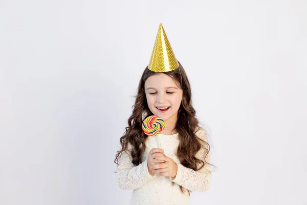 Uma Menina Bonita Está Comendo Grande Pirulito Chapéu Festivo Fundo — Fotografia de Stock