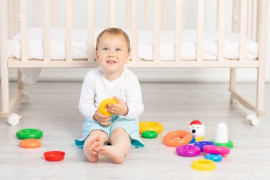 Küçük bir çocuk. 2 yaşında. Beşiğin yanında oynuyor.