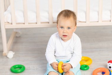 Küçük bir çocuğun portresi. 2 yaşında. Beşiğin yanında oynuyor.