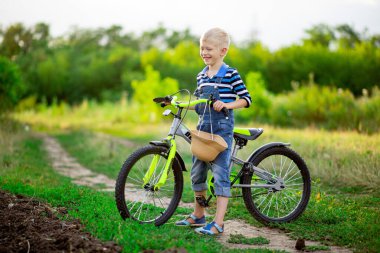 Bisikletli mutlu sarışın erkek bebek yazın bir tarlada duruyor, çocuk yaşam tarzı.