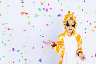 Parlak turuncu zürafa kostümü giymiş neşeli bir çocuk elini beyaz, izole bir arkaplanda tutuyor.