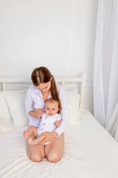 Genç Bir Anne Altı Aylık Bir Bebekle Beyaz Bir Yatakta — Stok fotoğraf