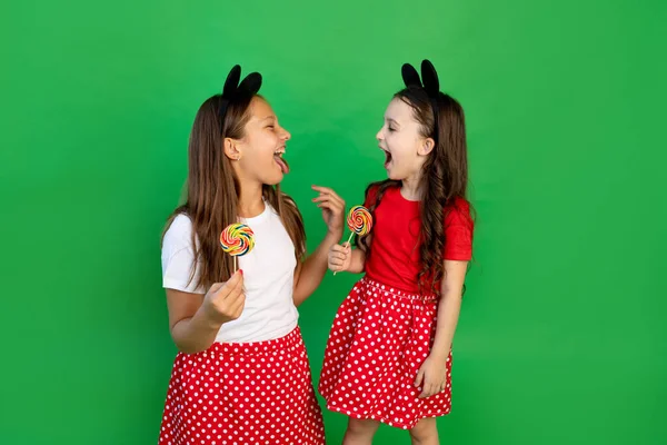 Χαριτωμένα Κοριτσάκια Κόκκινα Ρούχα Ένα Πράσινο Απομονωμένο Φόντο Τρώνε Μεγάλα — Φωτογραφία Αρχείου