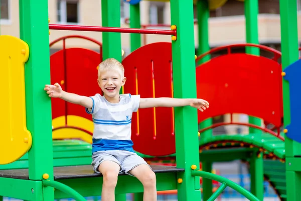 5-6 yaşındaki mutlu erkek bebek yazın bahçedeki oyun bahçesinde oynuyor. Çocuk yaşam tarzı