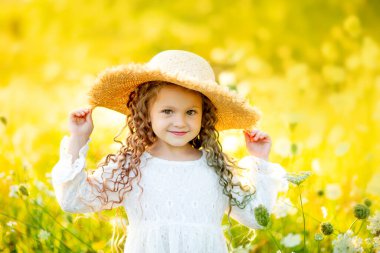 Yazın sarı bir tarlada çiçekli hasır şapkalı neşeli güzel kız.