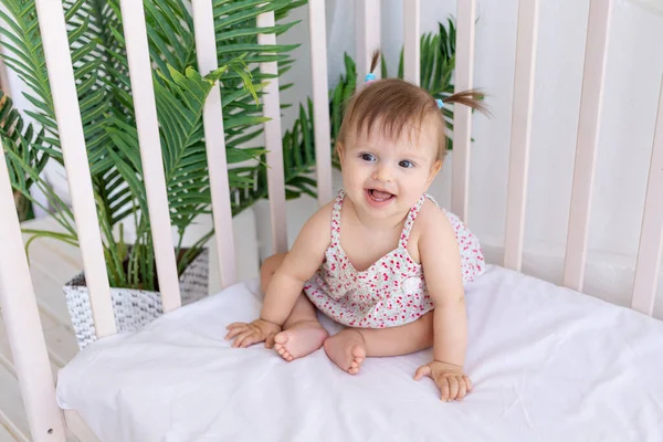 Uma Menina Senta Quarto Brilhante Berço Sorri — Fotografia de Stock