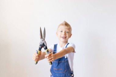 Çocuk, mimar, metal makası duvarın beyaz arka planında tutar. Makas odak noktasında, yazı için boşluk, tamir konsepti.