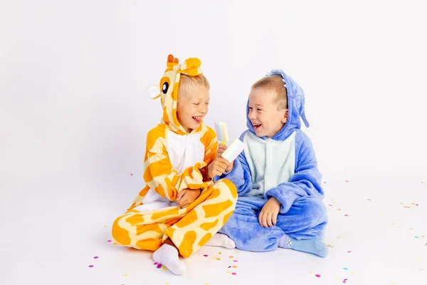 两个穿着鲜艳服装的小男孩穿着白色的隔离背景的衣服 一边吃着冰激凌一边放纵 孩子们的生日 发短信的地方 — 图库照片