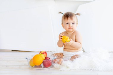 Bir çocuk mavi tişörtlü beş yaşında bir çocuk beyaz bir ofiste leylak bir sandalyede oturuyor.