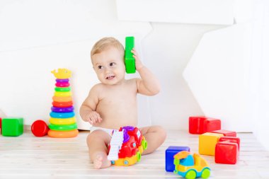 Küçük bir çocuk. Altı aylık bir çocuk. Parlak beyaz bir odada parlak küplerle oynuyor.
