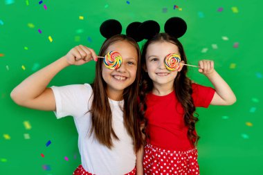 Yeşil izole edilmiş, tatlı küçük kızlar. Gözlerinde lolipoplar var. Ders için boşluk. Tatil konsepti