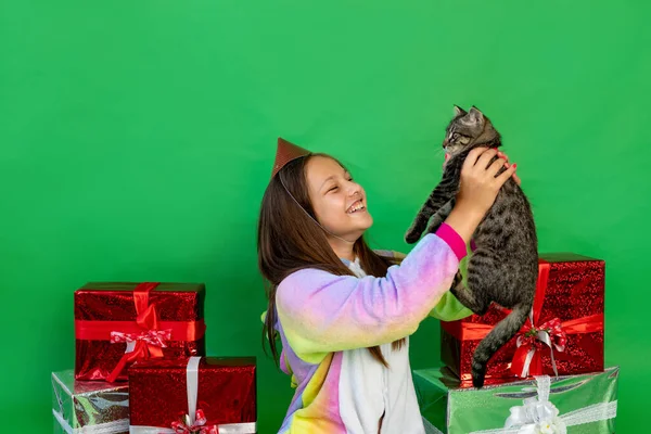 the child was given a cat For his birthday. Green isolated background with gifts Space for text. New year and Christmas concept, animal as a gift