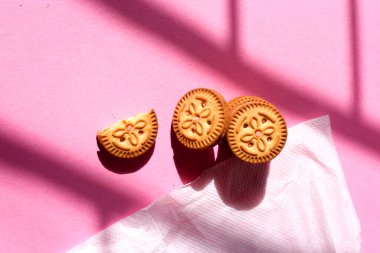 Pembe izole arka planda üst üste yığılmış bisküvi manzarası. Tatlı bisküviler, kremalı bisküviler, birikmiş bisküviler.