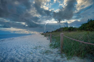 Sahilde ışıklandırma. Gökyüzündeki kara bulutlar.