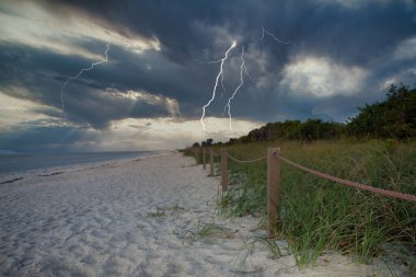 Sahilde ışıklandırma. Gökyüzündeki kara bulutlar.
