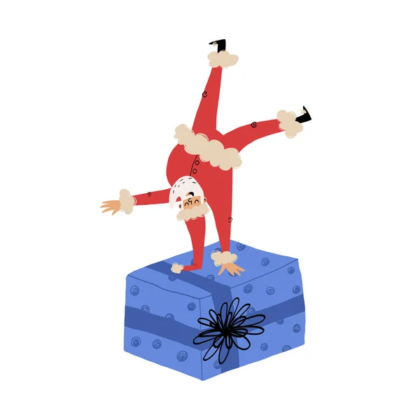 Cute break-dancer Santa stands upside down on one hand on huge gift box with Christmas present in it. — Stock Vector