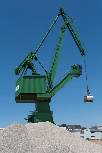 Exterior view of a cement factory with green crane.