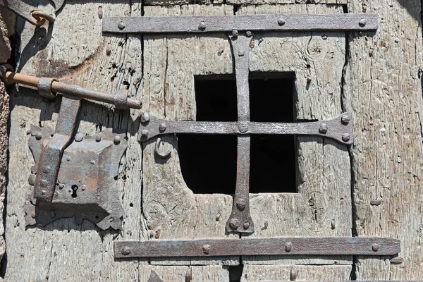 Stare średniowieczne drewniane drzwi z oknami i okuciami z kutego żelaza — Zdjęcie stockowe