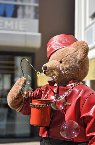 Urso de pelúcia grande com chapéu vermelho e jaqueta de couro sopra bolha de sabão — Fotografia de Stock