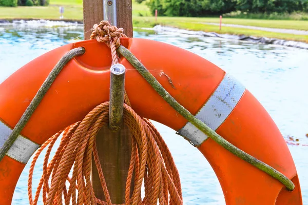 Arkasında göl olan turuncu bir can simidi halkası.