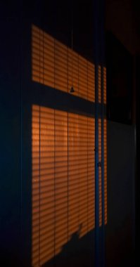 Pencereden süzülen gölgelerin bir görüntüsü güneş batarken iç duvarın üzerine kapanıyor..