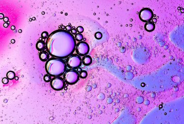 Pembe ve mavinin tonlarında yağ ve su kabarcıklarından oluşan bir makro fotoğraf.