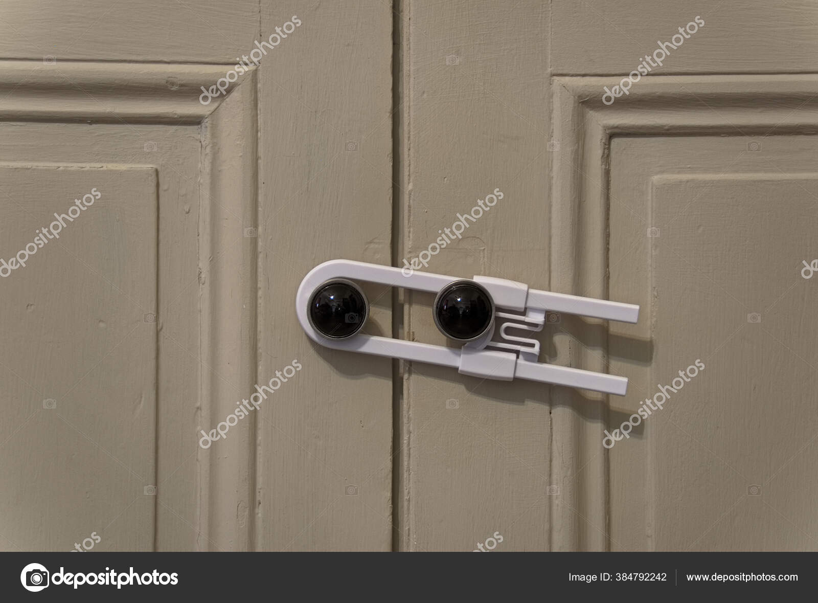 Close View White Child Safety Lock Holding Two Cabinet Doors Stock.