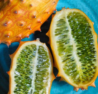 Mavi bir tabakta, kiwano meyvesinin içindeki yeşil ve doğal güneş ışığıyla aydınlatılıyor.