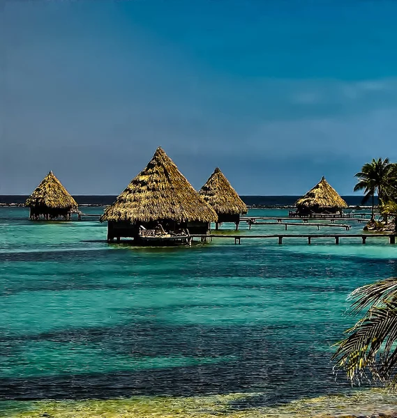 Sığ suların üzerindeki dört sazdan çatı kabininin manzarası, Glover 's Adoll, Belize sahillerinde.