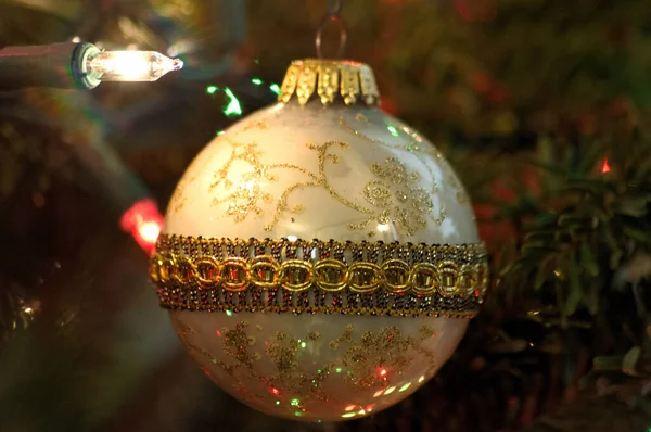 Beyaz bir Noel ipliği ışığında eski moda beyaz ve altın bir Noel ampulünün yakın görüntüsü