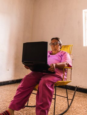 Büyükannem bilgisayar öğreniyor odada tek başına rahatça oturuyor.