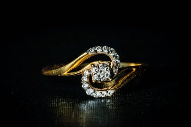 Koyu arkaplanda altın elmas bir yüzüğün makro çekimi