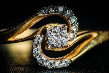 Koyu arkaplanda altın elmas bir yüzüğün makro çekimi