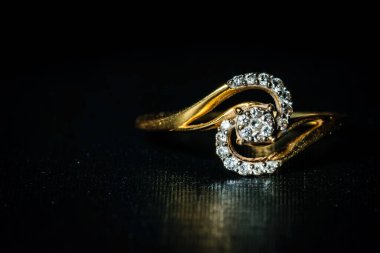 Sağ arka planda saklanmış altın bir elmas yüzüğün makro çekimi. Soldaki metin için boşluk